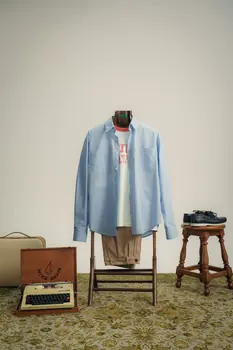 Camisa azul numa cadeira, com mala e máquina de escrever