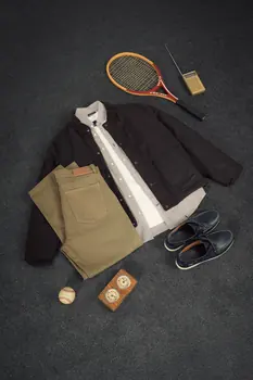 Casaco escuro, camisa branca, calças e sapatos, com raqueta